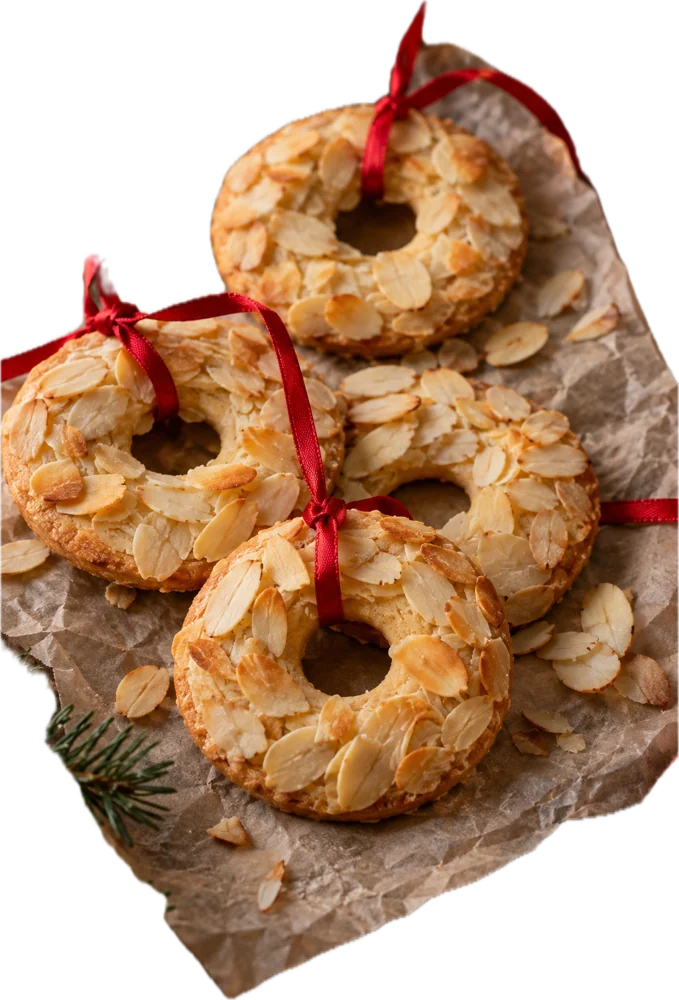 Kerstkransjes met amandelschaafsel en een rood lintje op bakpapier